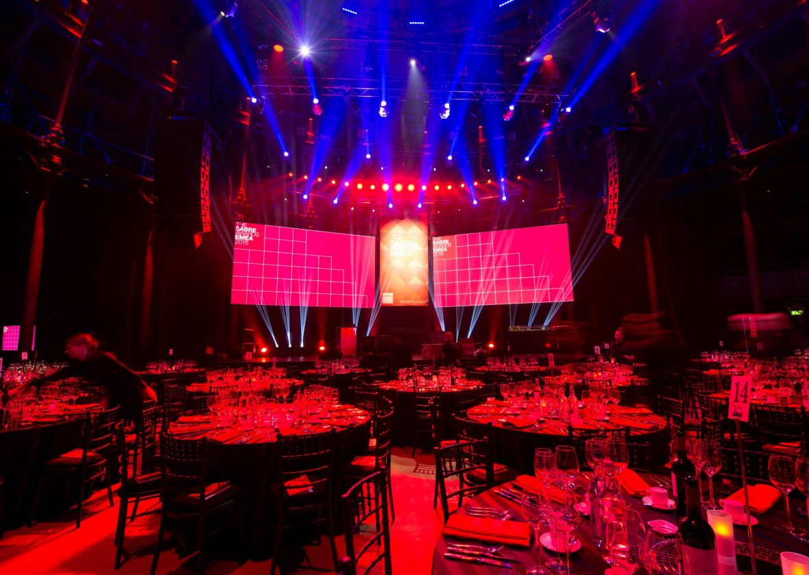Runde bord dekket på foran en scene med rødt lys hvor det står "The Sabre Awards EMEA 2015"