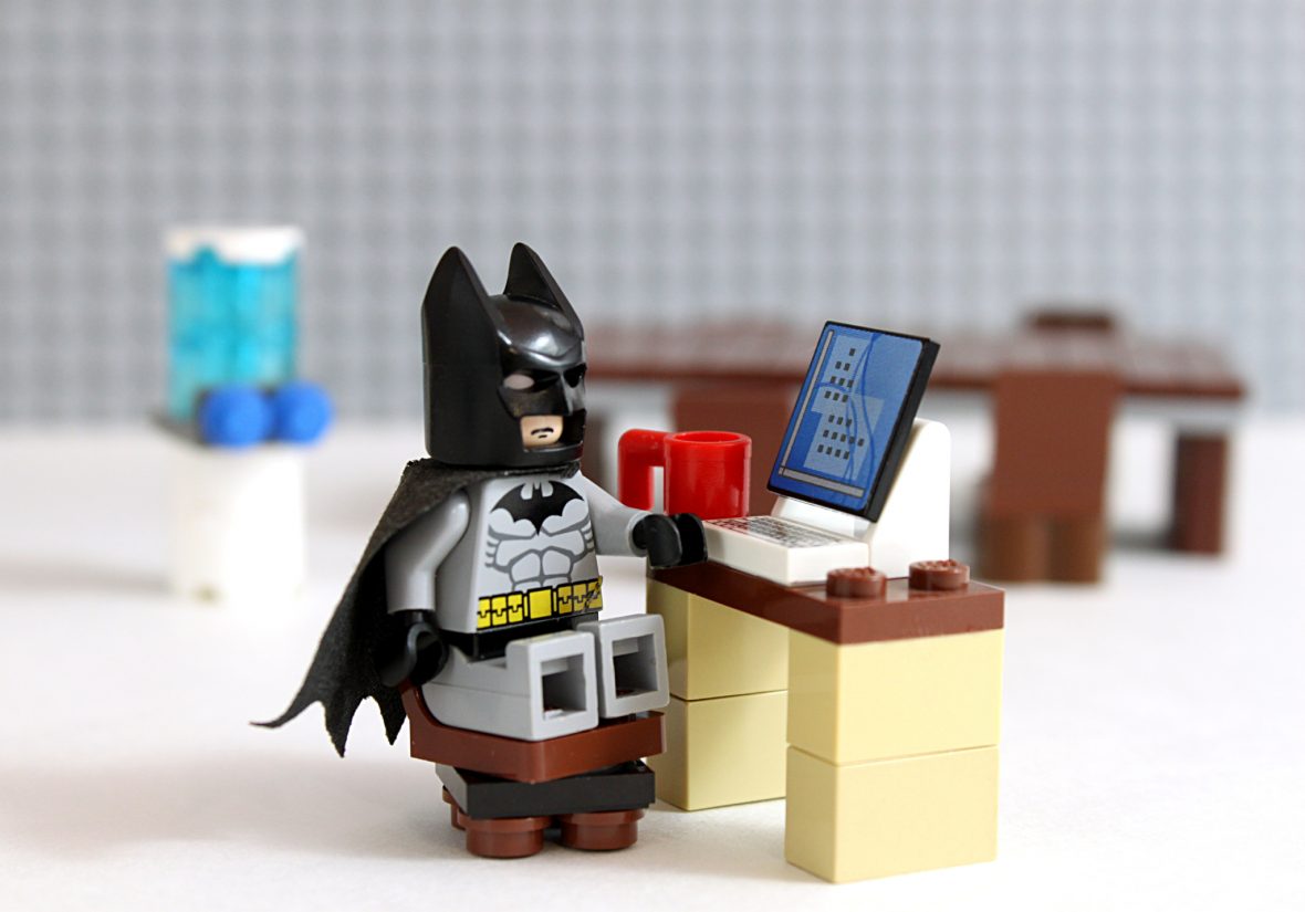 Lego Batman sitter på legostol foran legopult og data med kaffekopp