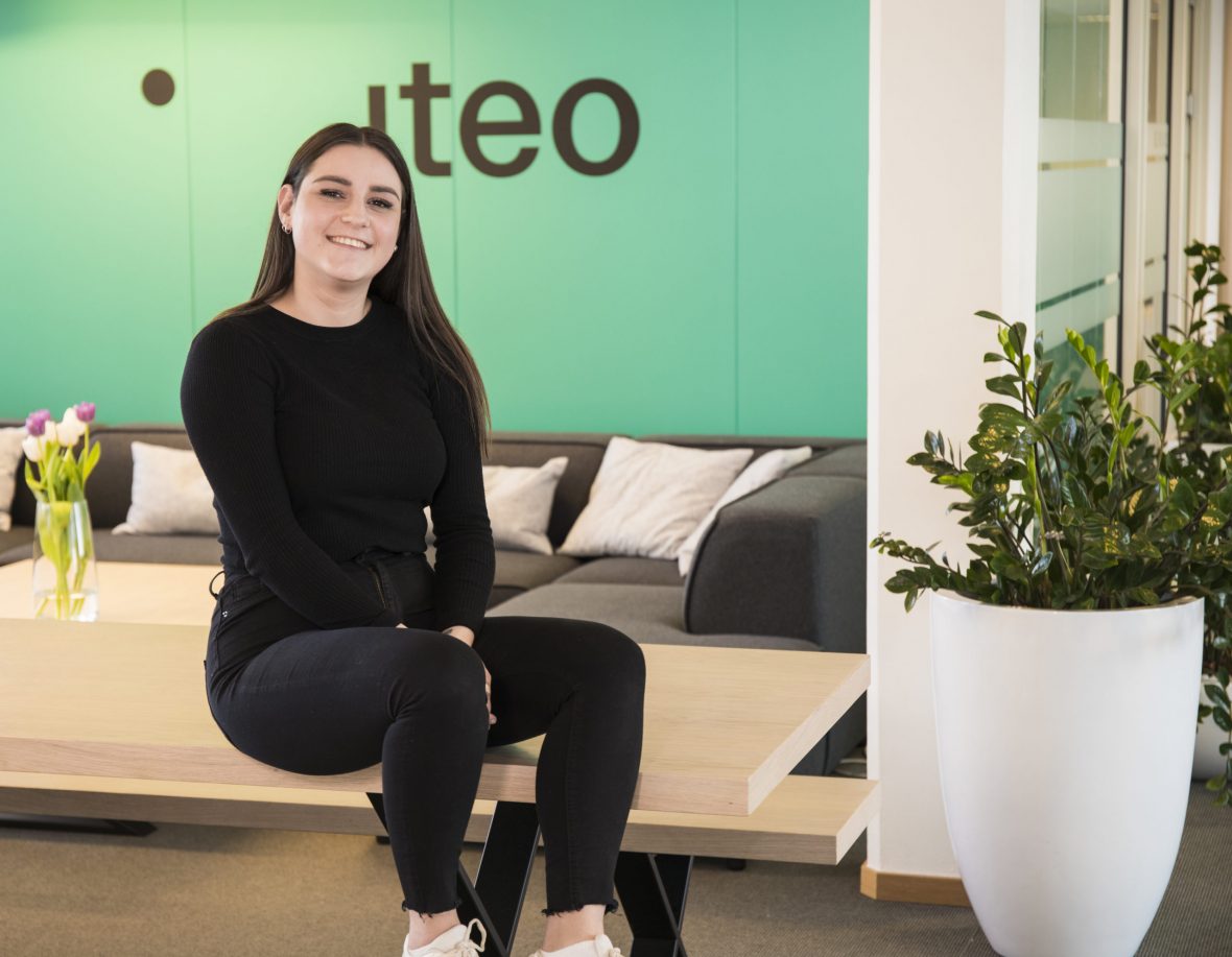Performance-rådgiver, Ida Marie Köhl, sitter smilende på et bord foran Iteos logo.