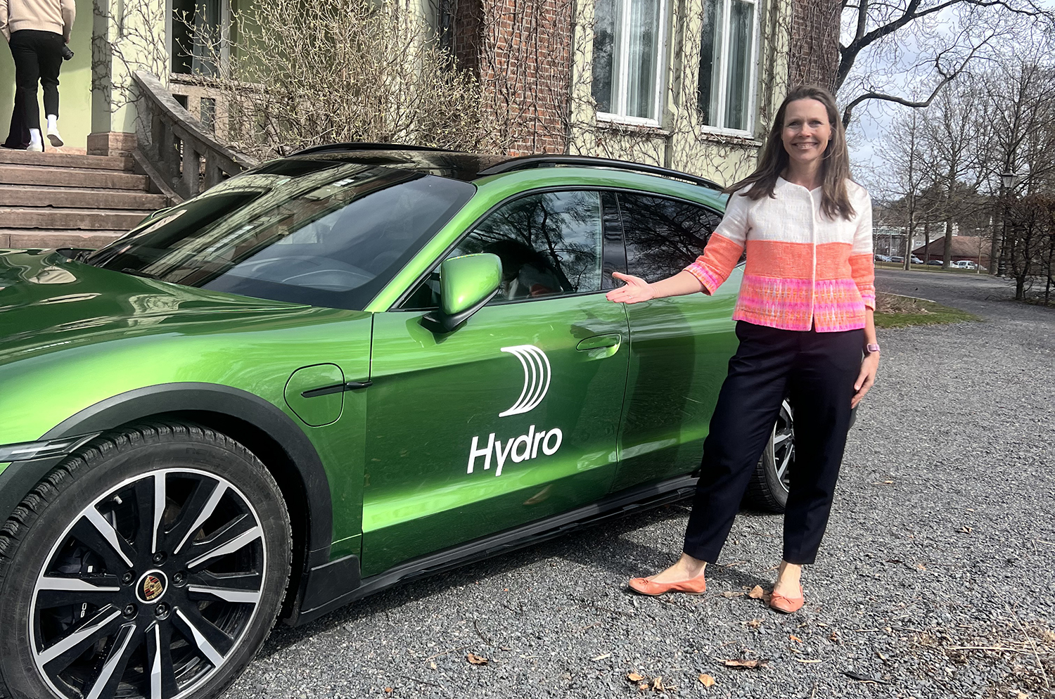 Bilde fra lansering av Porsche og Hydro-samarbeid med Executive Vice President for Kommunikasjon og Myndighetskontakt i Hydro, Therese Rød Holm, som står foran en grønn bil. Foto: Hilde Haugen Kallevig, Hydro.